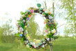 beautiful decorative Spring wreath hanging in garden, green natural background. symbol of Easter holiday, Ostara. spring festival decor.