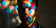 Young man's face is illuminated with a mosaic of colorful light spots, contrasting with shadow