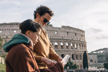 Mother and daughter looking at a map of the city,  the woman is wearing a sunglasses and the daughter is wearing a brown jacket