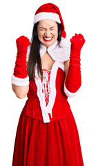 Poster - Young beautiful caucasian woman wearing santa claus costume excited for success with arms raised and eyes closed celebrating victory smiling. winner concept.