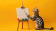Striped cat stands on hind legs holding paintbrush, facing easel vibrant yellow background