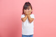 © Ilshat - Shocked terrified baby girl popping eyes covers mouth with palms hears shocking rumor stands speechless dressed in casual t shirt isolated over pink background