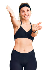 Wall Mural - Young beautiful blonde woman wearing sportswear looking at the camera smiling with open arms for hug. cheerful expression embracing happiness.