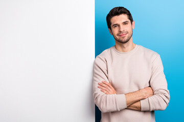 Poster - Photo of confident sweet man wear beige sweatshirt arms crossed poster empty space isolated blue color background