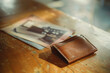 A worn-out, empty wallet rests on a simple wooden table, beside a small, faded photograph of a once bustling workplace