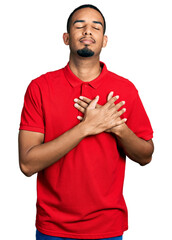 Wall Mural - Young african american man wearing casual polo smiling with hands on chest, eyes closed with grateful gesture on face. health concept.