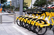A beautiful yellow bicycle is parked in a designated area. On the side of the road in the city