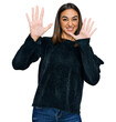 Beautiful brunette woman wearing elegant sweater afraid and terrified with fear expression stop gesture with hands, shouting in shock. panic concept.