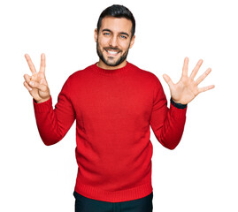 Canvas Print - Young hispanic man wearing casual clothes showing and pointing up with fingers number seven while smiling confident and happy.