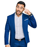 Fototapeta Koty - Young hispanic man wearing business jacket smiling pointing to head with one finger, great idea or thought, good memory