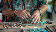 A street vendor arranges various pieces of handmade jewelry on a folding table - part of a lively outdoor market