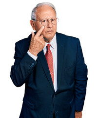 Poster - Senior man with grey hair wearing business suit and glasses pointing to the eye watching you gesture, suspicious expression