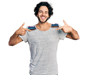 Sticker - Young hispanic man wearing casual t shirt looking confident with smile on face, pointing oneself with fingers proud and happy.