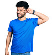 © Krakenimages.com - Young arab man with beard wearing casual blue t shirt doing peace symbol with fingers over face, smiling cheerful showing victory