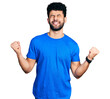 © Krakenimages.com - Young arab man with beard wearing casual blue t shirt very happy and excited doing winner gesture with arms raised, smiling and screaming for success. celebration concept.