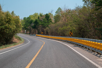 Wall Mural - long curvy forest asphalt road over the hills. beautiful curved road in the forest. side view of roa
