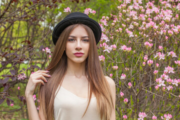 Cheerful fashion model with long brown hair and natural makeup against floral background outdoor