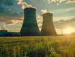 Two large power plants are in a field with a beautiful sunset in the background