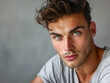 An attractive man with green eyes and trendy hairstyle is posing looking at a camera 