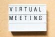 Lightbox with word virtual meeting on wood background