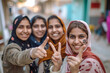 Group of young women showing ink marked fingers outside polling station or booth after casting their votes 