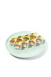 Maki sushi with sesame outside, tempura shrimp inside topped spicy sauce and microgreens. Spicy shrimp maki roll on ceramic plate isolated on white background Sushi roll with crispy prawn on plate