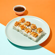 Baked maki sushi in ceramic plate on coloured background. Sushi roll with shrimp tartare in trendy style on orange and blue colour backdrop Maki roll with hard shadows in minimal style