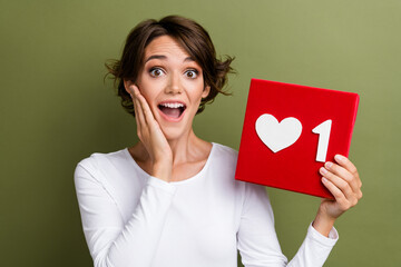 Wall Mural - Photo portrait of lovely young lady excited shocked hold heart icon dressed stylish white garment isolated on khaki color background