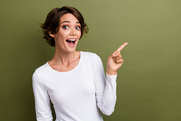 Wall Mural - Portrait of funny excited promoter lady directing finger empty space shopping adv ads ad isolated khaki green color background