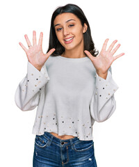 Young hispanic girl wearing casual clothes showing and pointing up with fingers number ten while smiling confident and happy.