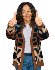 Poster - Middle age hispanic woman wearing casual clothes approving doing positive gesture with hand, thumbs up smiling and happy for success. winner gesture.