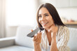 © Prostock-studio - Smiling woman holding phone for voice command