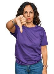 Wall Mural - Middle age hispanic woman wearing casual clothes looking unhappy and angry showing rejection and negative with thumbs down gesture. bad expression.