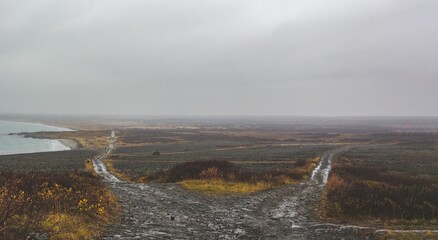 Barren landscape with water on the side, under gray foggy sky in Murmansk, Russia