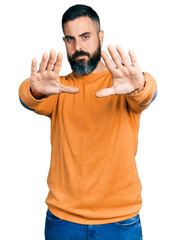 Wall Mural - Hispanic man with beard wearing casual winter sweater doing frame using hands palms and fingers, camera perspective