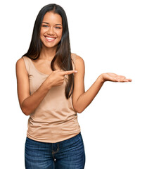 Canvas Print - Beautiful hispanic woman wearing casual clothes amazed and smiling to the camera while presenting with hand and pointing with finger.