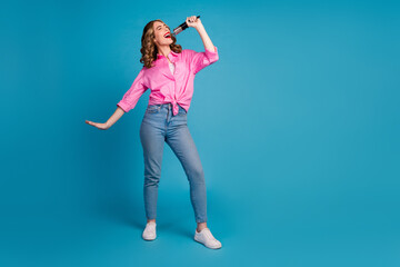 Poster - Full body photo of pretty young girl hold microphone singing wear trendy pink outfit hairdo isolated on blue color background