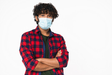 Confident young Indian man with arms crossed wearing protective face mask isolated over white background. Coronavirus, pandemic concept