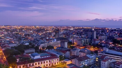 Wall Mural - Panoramic aerial overview on Rooftops of Porto's old town on a warm spring evening timelapse day to night transition from above, Porto, Portugal. Lights turning on