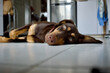 Front view of a cute young mixed breed dog head with green eyes lying on a kitchen with focus on the foreground and a fridge in the background.