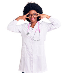 Sticker - Young african american woman wearing doctor coat and stethoscope doing peace symbol with fingers over face, smiling cheerful showing victory