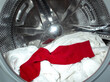 Red sock with white clothes in the washing machine drum, it is important not to mix the colors when washing