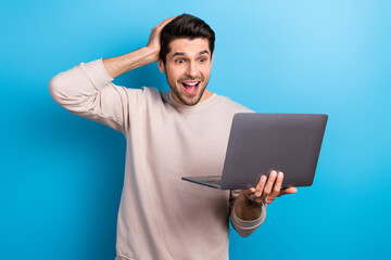Fototapete - Portrait of young impressed man use laptop unbelievable reaction wear beige sweatshirt isolated on blue color background