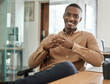 Smiling young African businessman sitting at his office desk