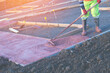 Builders pouring and levelling wet ready-mix concrete into formwork   during new footpath construction