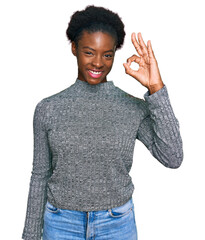 Wall Mural - Young african american girl wearing casual clothes smiling positive doing ok sign with hand and fingers. successful expression.