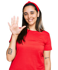 Wall Mural - Young hispanic woman wearing casual clothes showing and pointing up with fingers number five while smiling confident and happy.