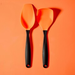 A silicone spatula set on a bright orange background, showcasing its flexibility and heat resistance.