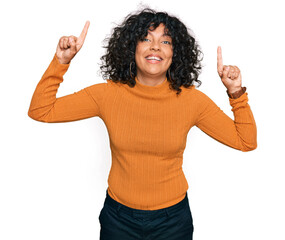 Poster - Young hispanic woman wearing casual clothes smiling amazed and surprised and pointing up with fingers and raised arms.