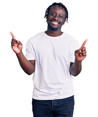 Canvas Print - Young african american man with braids wearing casual white tshirt smiling confident pointing with fingers to different directions. copy space for advertisement